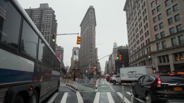 Straßenansicht des Verkehrs vor dem Flatiron Building in New York City. Bus und Autos auf einer Straßenkreuzung in der Nähe des Fuller Building in NYC — Stockvideo