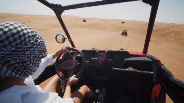 Femme conduisant un buggy dunaire dans le désert. Pov de jeune femme avec la tête couverte conduisant un véhicule hors route dans le désert — Video