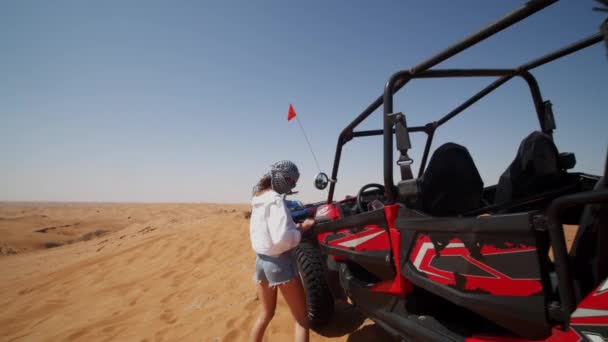 사막 여행중 모래 마차를 탄 젊은 여성. 사막에서 교통사고 차량을 운전 할 준비를 하고 있는 여자 — 비디오