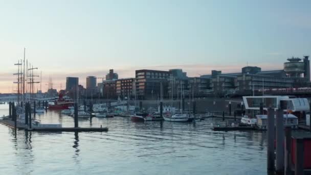 Rendah dolly pandangan udara dari perahu berlabuh dan perahu layar di pelabuhan Hamburg saat matahari terbenam — Stok Video