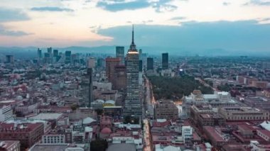 Mexico City şehir merkezindeki Torre Latinoamericana gökdeleninin batan akşam ışığı ve büyük şehrin üzerinde batan güneş, yukarıdan insansız hava aracı görüntüsü