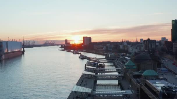 Stijgend uitzicht vanuit de lucht op de haven van Hamburg in de zonsondergang met rustige rivier de Elbe die door de stad stroomt — Stockvideo