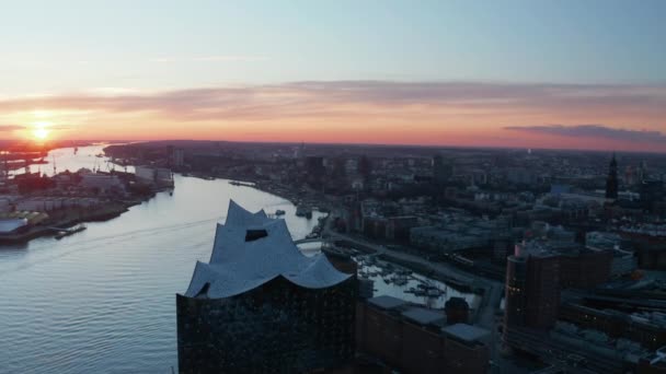 Gün batımında Elbe nehri kıyısındaki Hamburg şehir merkezindeki Elbphilharmonie binasının hava aracı görüntüsü — Stok video