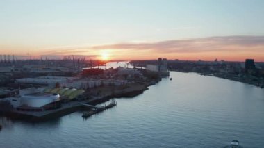 Hamburg limanındaki sanayi bölgesindeki depoların önünden geçen Elbe nehri boyunca giden bir teknenin hava aracı görüntüsü.