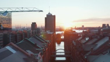 Hamburg limanında gün batımında Speicherstadt deposunun arkasında Elbe nehri kıyısındaki bölge binaları.