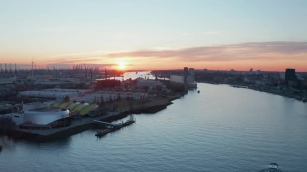 Hamburg limanındaki sanayi bölgesindeki depoların önünden geçen Elbe nehri boyunca giden bir teknenin hava aracı görüntüsü. — Stok video