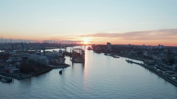 Склады в промышленном районе Гамбурга с грузовым портом на расстоянии во время захода солнца — стоковое видео