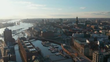 Elbe Nehri 'nde tekneleri ve nehir kıyısında apartmanları olan Hamburg limanının havadan yükselen manzarası