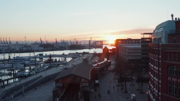 Luchtfoto dolly in zicht na een trein langs de rivier de Elbe in Hamburg centrum bij zonsondergang — Stockvideo