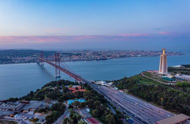 Alacakaranlık vakti, Lizbon, Portekiz 'de Tagus nehri üzerindeki asma köprüye giden çok şeritli yol manzarası.