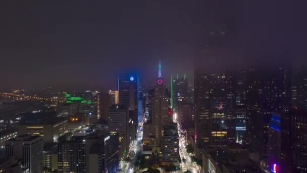 Wieczorny hiper filmik z wysokimi drapaczami chmur w dzielnicy biznesowej, Dallas, USA. Widok z drona lecącego w kierunku dużego neonu zegar na szczycie budynku. — Wideo stockowe