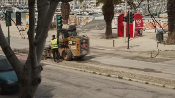 葡萄牙拉各斯的公路工人正在准备当地的沥青路面修理工作。用机器清洁街道。黄色山猫摘除顶层. — 图库视频影像