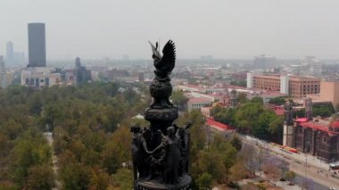 Yüksek sütunlarda bulunan heykellerin etrafında uçan insansız hava aracı. Rakamların ve Mexico City Panorama 'nın dairesel manzarası. Şehirdeki bina çeşitliliği.