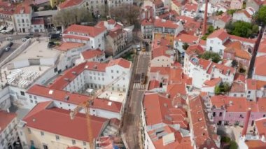 Lizbon şehir merkezindeki renkli geleneksel evler arasında sürüş yapan ikonik tramvayların hava görüntüsü