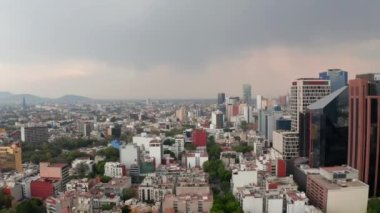 Şehirdeki çeşitli binaların manzarası yükseldi. Alt katlarda evleri olan uzun iş binaları. Drone kamerası yağmurdan önce yavaşça iniyor.
