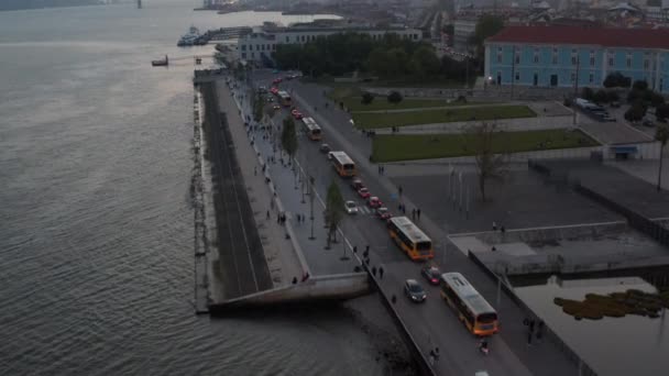 Revelação aérea do movimentado trânsito automóvel na costa de Lisboa, Portugal com a icónica ponte vermelha Ponte 25 de Abril ao fundo — Vídeo de Stock