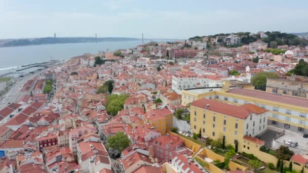 ポルトガルのリスボンの密集した都市の中心部にあるカラフルな家の屋根の上を飛んでいます。丘の上の住宅の空中広いパノラマビュー — ストック動画