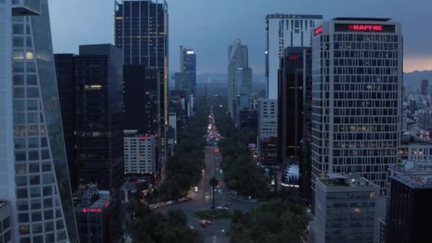 Σύγχρονα ψηλά κτίρια κατά μήκος της κεντρικής λεωφόρου μετά το ηλιοβασίλεμα. Προς τα πίσω ιπτάμενο drone άποψη του δρόμου βιασύνη στην επιχειρηματική περιοχή της πόλης του Μεξικού. — Αρχείο Βίντεο