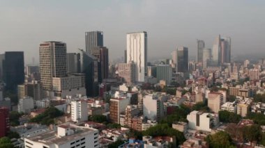 Şehir merkezinin havadan görüntüsü. İHA, yüksek ofis binalarına doğru uçuyor. Hava kirliliği nedeniyle görüş mesafesi sınırlı. Mexico City, Meksika.