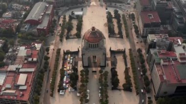 Plaza de la Republica 'daki ünlü Devrim Anıtı' nın insansız hava görüntüsü. Kamera açısı şehir panoramasını güneşe doğru eğiyor. Mexico City, Meksika.