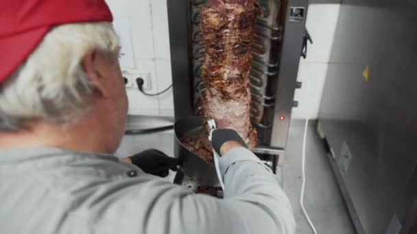 Κοντινή άποψη του ταχυδακτυλουργού κοπή του κρέατος για το γεύμα kebab Doner από περιστρεφόμενο ραβδί κρέας στο παραδοσιακό πιάτο της Μέσης Ανατολής — Αρχείο Βίντεο