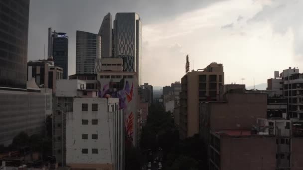 Drone kamera letí dopředu mezi vysokými kancelářskými budovami v centru města. Obloha před silným deštěm. Mexico city, Mexico. — Stock video