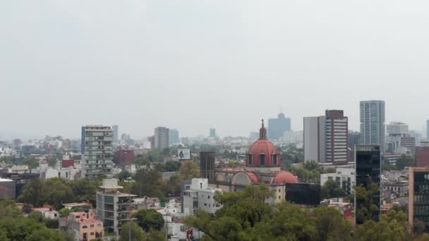 Drone comenzando desde el parque y subiendo sobre la iglesia en la zona residencial de la ciudad. Vista aérea del paisaje urbano. Cámara inclinada hacia el techo rojo. Ciudad de México, México. — Vídeo de stock