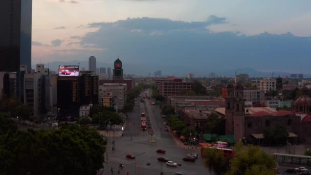 Kvällsdrönarflyg ovanför korsningen av de viktigaste flerfiliga gatorna i centrum. Olika byggnader i stan. Mexico City, Mexiko. — Stockvideo