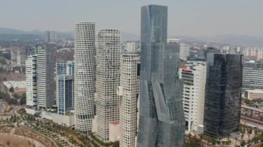 Torre Paradox 'un ve etrafındaki modern yüksek binaların insansız hava aracı görüntüsü. Kamera dönüyor ve aşağı eğiliyor. Mexico City, Meksika.