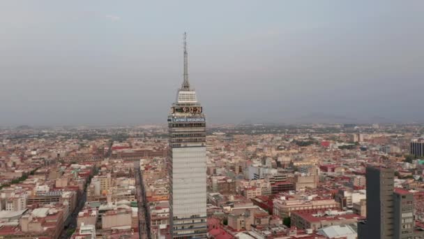 Vista aérea del edificio alto Torre Latinoamericana. Cámara volando alrededor de la parte superior del rascacielos, paisaje urbano en el fondo. Ciudad de México, México. — Vídeos de Stock