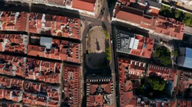 Lizbon şehir merkezindeki geleneksel Portekiz evlerinin kırmızı çatılarıyla çevrili bir anıtı olan küçük bir halk meydanının yukarıdan aşağıya doğru uzanan manzarası.