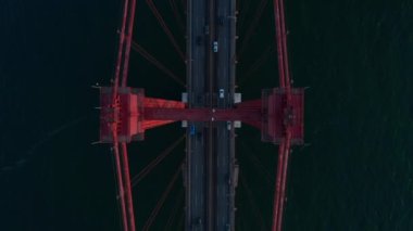 Kuşların tepeden aşağı uçuşu yoğun araba trafiğini Lizbon, Portekiz 'de denizin karşısındaki 25. Ponte de Abril Köprüsü' nde görüyor.