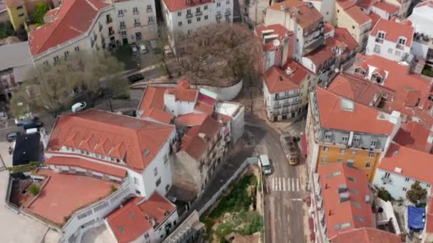 Veduta aerea aerea di un tram giallo che gira un angolo sui binari nel centro urbano di Lisbona, Portogallo — Video Stock