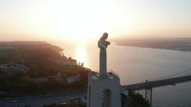 İsa 'nın Sığınağı' nın çarpıcı hava yörüngesinde akşam vakti tepedeki Kral heykeli Ponte 25 de Abril kırmızı köprüsünün ve Lizbon şehir merkezinin deniz üzerinde olduğu ortaya çıktı.