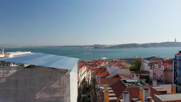 Aerial dolly in view of red rooftops of traditional colorful European buildings and boats at sea off the shore of Lisbon, Portugal — Stock Video