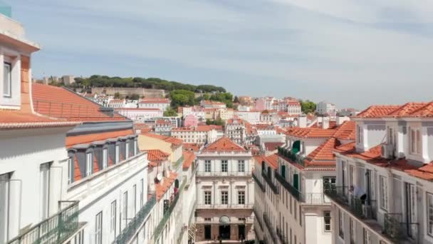 Aerial dolly in view of colorful traditional European houses with orange rooftops and old castle on the hill in Lisbon city center — Stock Video