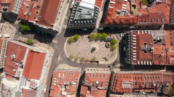 Üstten aşağı kuşların bakış açısı, Lizbon şehir merkezindeki dar sokaklar üzerinde bir anıt ve arabalar taşıyan küçük geleneksel meydanı gösteriyor. — Stok video