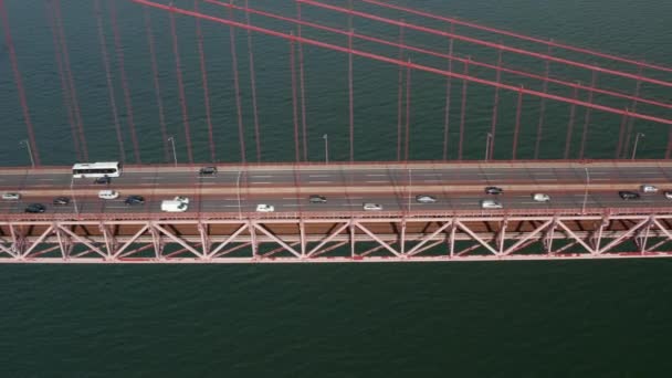 Vista laterale scorrevole del traffico multi corsia occupato attraverso un ponte rosso sul mare. Auto che attraversano Ponte 25 de Abril ponte sospeso a Lisbona, Portogallo — Video Stock