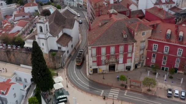 Efter antenn skott av färgglada gula traditionella spårvagn kör på spåren mellan hus i centrum av Lissabon, Portugal — Stockvideo
