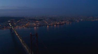 Nehir kıyısındaki gece panoramik hava manzarası. Köprüde ve şehir merkezindeki sokak lambasında giden arabaların ışığı. Uçan İHA 'dan görüntüler. Lizbon, Portekiz 'in başkenti.