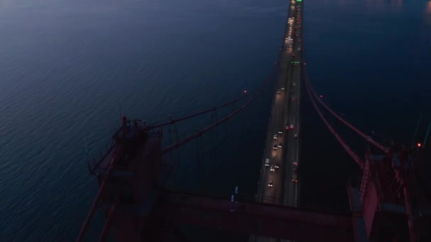 Luchtfoto van auto 's die na zonsondergang op de brug van 25 april rijden. Drone vliegt vooruit en draait. Lissabon, hoofdstad van Portugal. — Stockvideo