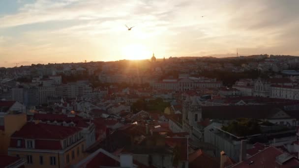 ドローンは歴史的な街の中心部を飛び回る。夕日に対する建物のシルエット。夕方の空中ビュー。ポルトガルの首都リスボン. — ストック動画
