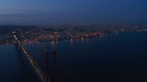 Nacht-Panorama-Luftaufnahme der Stadt am Flussufer. Licht von Autos, die auf einer Brücke und einer Straßenlaterne in der Innenstadt fahren. Aufnahmen von einer fliegenden Drohne. Lissabon, Hauptstadt von Portugal. — Stockvideo