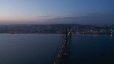 Lizbon ve Almada 'yı bağlayan 25 Nisan Köprüsü' nün gece hava görüntüsü. Birçok arabanın farları Tegus nehrinin üzerindeki otoban köprüsünde kaldı. İHA ileri uçuyor. Lizbon, Portekiz 'in başkenti.