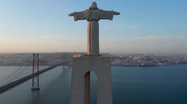 İHA kamera kaide ve heykel boyunca yükseliyor. Almada 'daki Kral Mabet İsa' nın akşam manzarası. Arka planda Tagus nehri üzerinde uzun bir köprü var. Lizbon, Portekiz 'in başkenti.