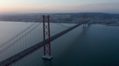 Aerial drone evening view of 25th of April Bridge over Tegus river. Silhouette of long cable-stayed bridge. Lisbon, capital of Portugal.