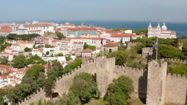 Luftaufnahme der steinernen Zinnen mit Verteidigungstürmen. Mittelalterliche Sankt-Georgs-Burg auf einem Hügel über historischen Häusern in der Stadt. Drohnen fliegen umher. Lissabon, Hauptstadt von Portugal. — Stockvideo