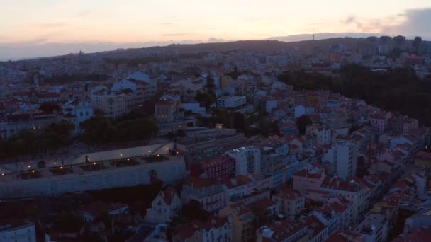 Vue aérienne de la ville du soir contre un ciel couchant et lumineux. Drone volant dans les rues. Lisbonne, capitale du Portugal. — Video