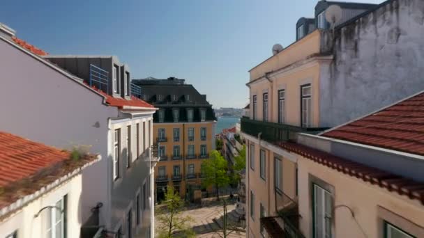 Cámara de drones volando en el nivel superior del piso sobre calles estrechas hacia la orilla del río. Lisboa, capital de Portugal. — Vídeo de stock