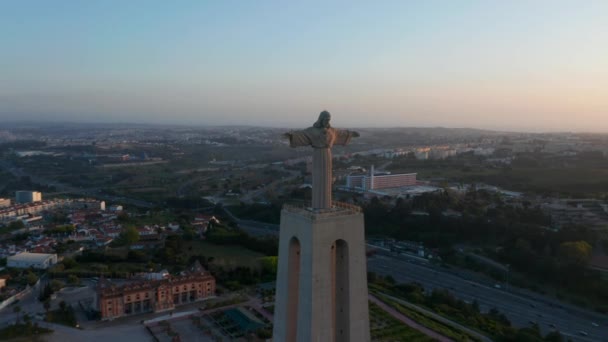 Gün batımında Almada 'daki Kral Mabet İsa' nın hava görüntüsü. Büyük İsa heykeli uzun beton kaidede duruyor. Lizbon, Portekiz 'in başkenti. — Stok video